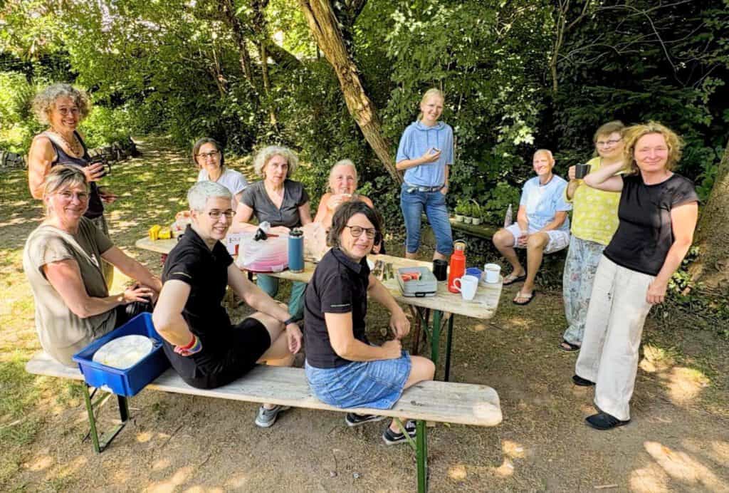 Tische und Bänke im Schatten, Frauen blicken zur Kamera